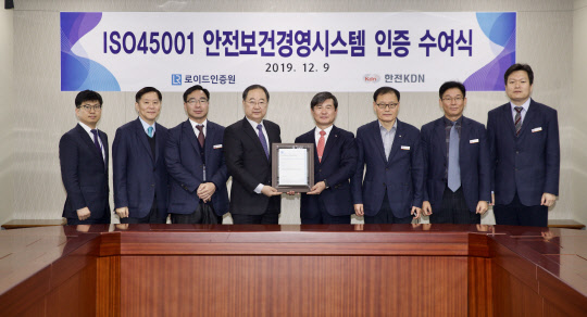 한전KDN은 9일 로이드인증원으로부터 ISO45001(안전보건경영시스템) 인증을 취득했다고 밝혔다. 박성철(왼쪽 다섯번째) 한전KDN 사장과 유상근 로이드인증원 대표가 이날 인증패를 함께 들어보이고 있다.    한전KDN 제공